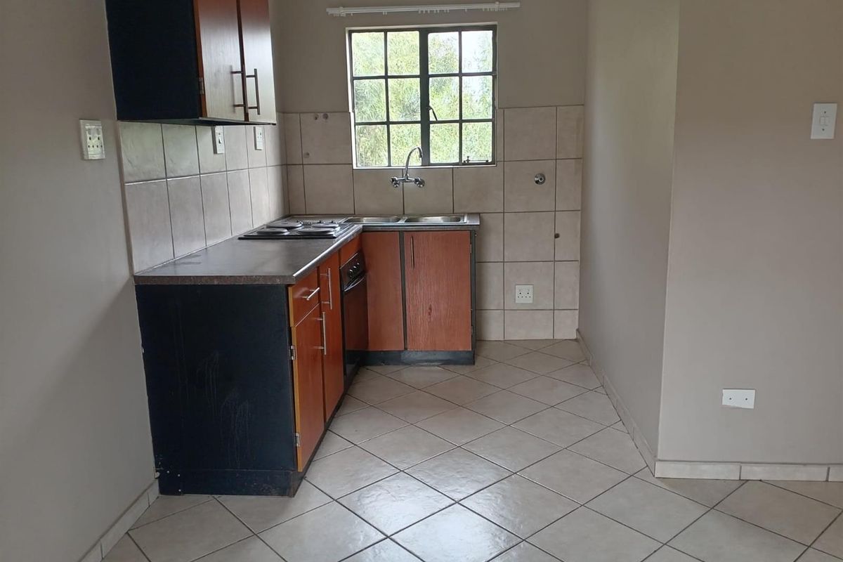 A functional kitchen featuring built-in cabinetry, laminate countertops, a stainless steel sink, and tiled flooring, offering a clean and practical workspace.