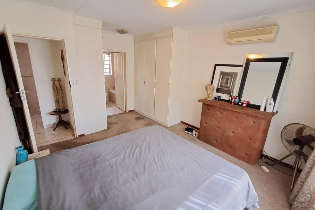 A bedroom featuring built-in cupboards, a wall-mounted air conditioning unit, and direct access to an en-suite bathroom.
