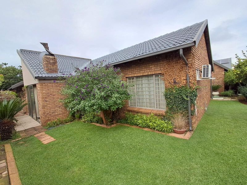 A view of the rear exterior of the townhouse, featuring face-brick construction, a tiled roof, and a well-maintained garden area.