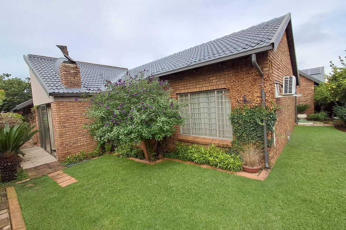 A view of the rear exterior of the townhouse, featuring face-brick construction, a tiled roof, and a well-maintained garden area.