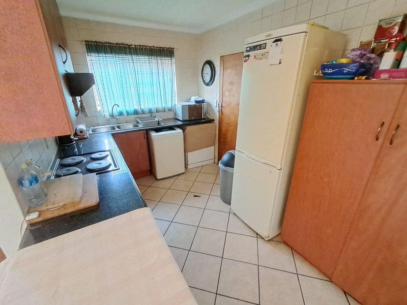A functional kitchen featuring built-in cabinetry, a tiled backsplash, a stainless steel sink, and a built-in electric hob.