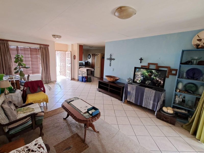 Open plan living area featuring tiled flooring, neutral walls, and direct access to the kitchen and exterior entrance.