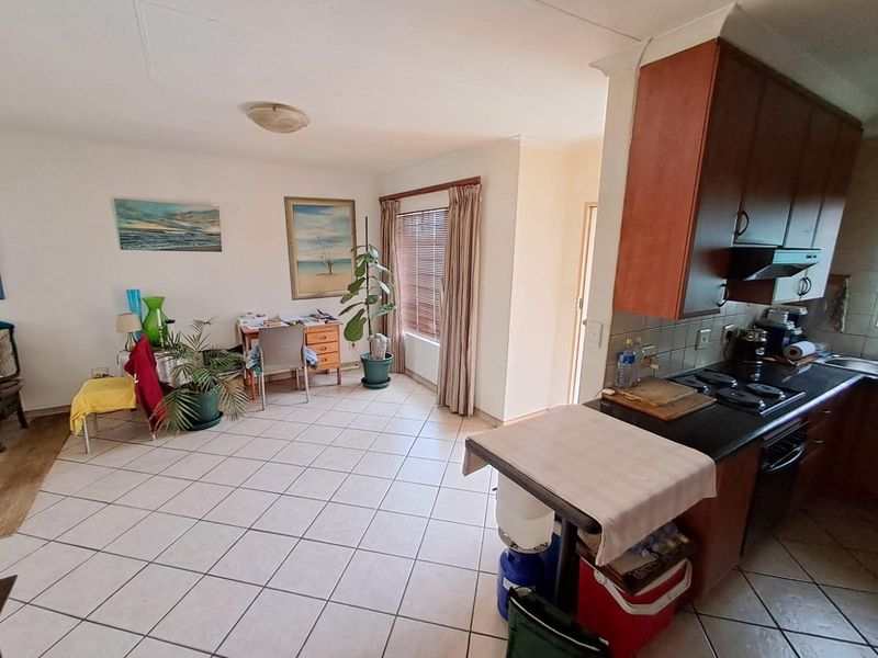 Open-plan living area featuring tiled flooring and a functional kitchen with built-in cabinetry, hob, and extractor fan.