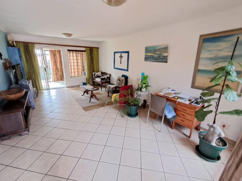 Spacious open-plan living area featuring tiled flooring, large windows, and sliding glass doors providing access to the outdoor patio.