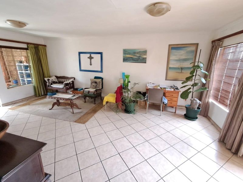 Spacious living area featuring neutral ceramic floor tiles, large windows with blinds, and direct access to an outdoor patio space.