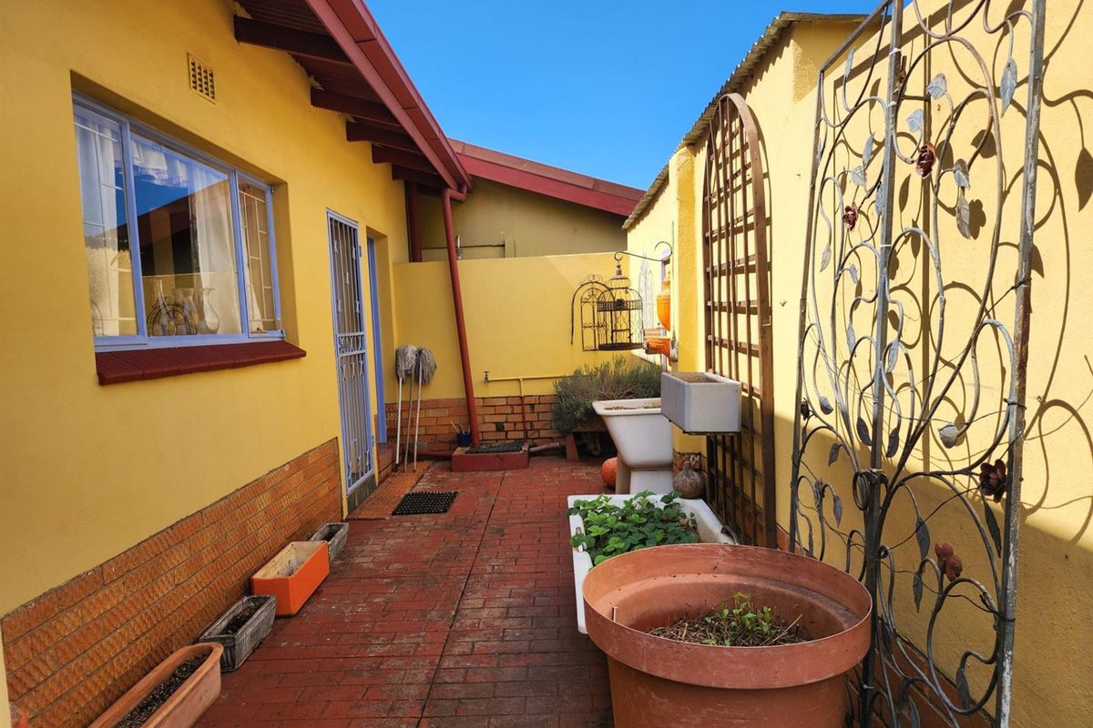 A paved side courtyard area featuring brick walls, a security gate, and a built-in utility sink, providing a functional outdoor space.