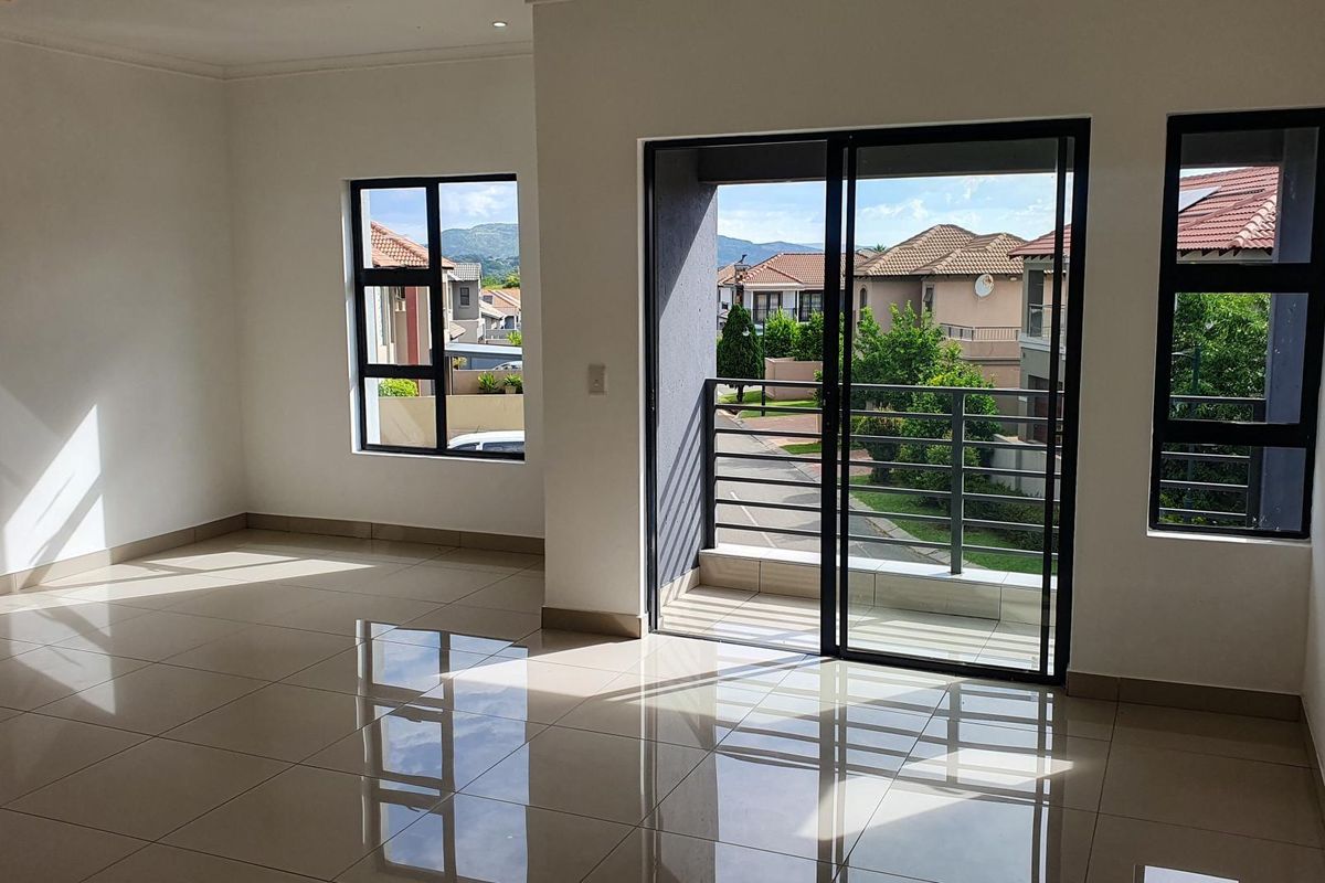 Bright and spacious living area featuring large windows, tiled flooring, and a sliding door leading to a private balcony with neighborhood views.