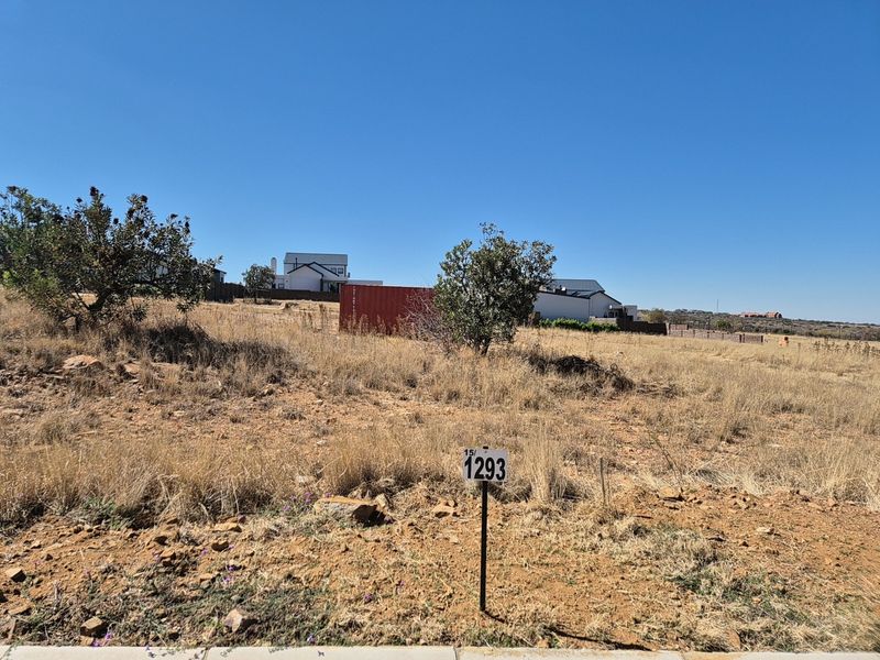 A view of a vacant residential plot featuring natural vegetation and a clear boundary marker, ready for development.