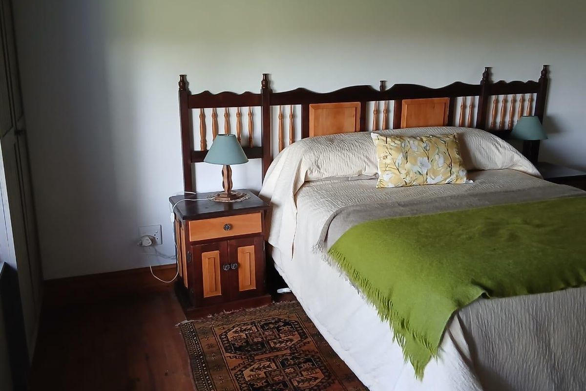 A cozy bedroom featuring warm timber flooring and a classic wooden headboard, creating a comfortable and inviting atmosphere.