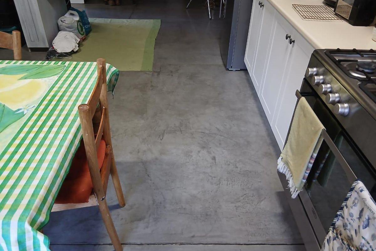 A functional kitchen area featuring white cabinetry, a stainless steel gas stove, and polished concrete flooring.