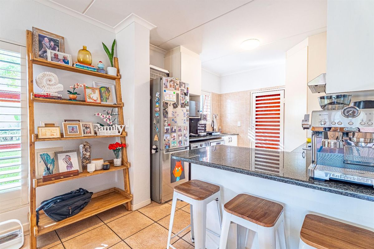 A functional kitchen featuring a granite breakfast bar, tiled flooring, and built-in cabinetry, providing a practical space for meal preparation and casual dining.