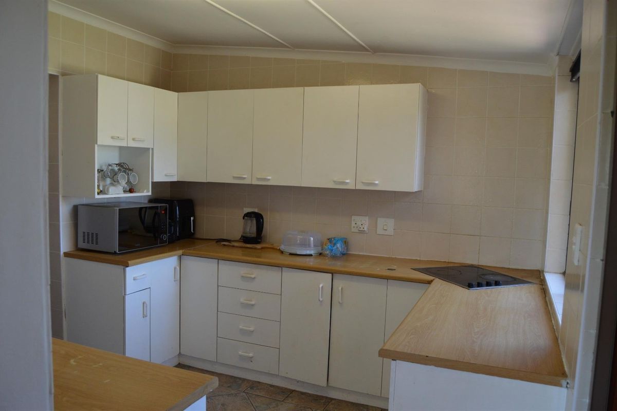 A functional kitchen featuring white cabinetry, laminate countertops, and tiled wall splashbacks, offering a practical layout for daily meal preparation.