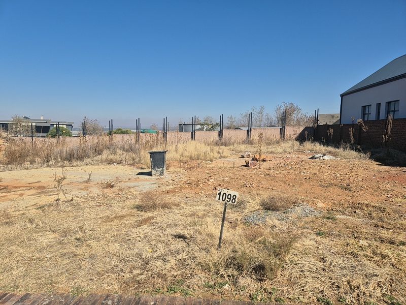 A vacant residential plot featuring a perimeter wall with security spikes, ready for development.