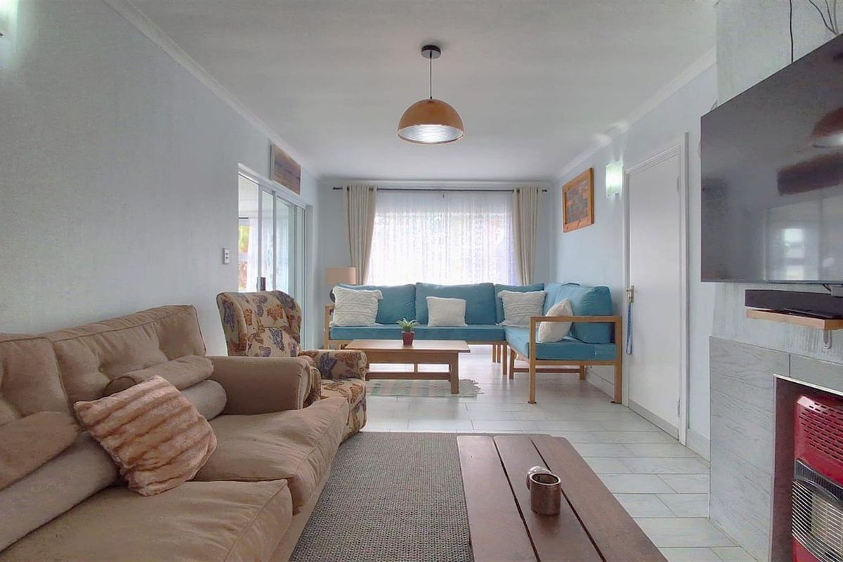 A bright living room featuring tiled flooring, a built-in fireplace, and sliding glass doors providing access to the outdoor area.