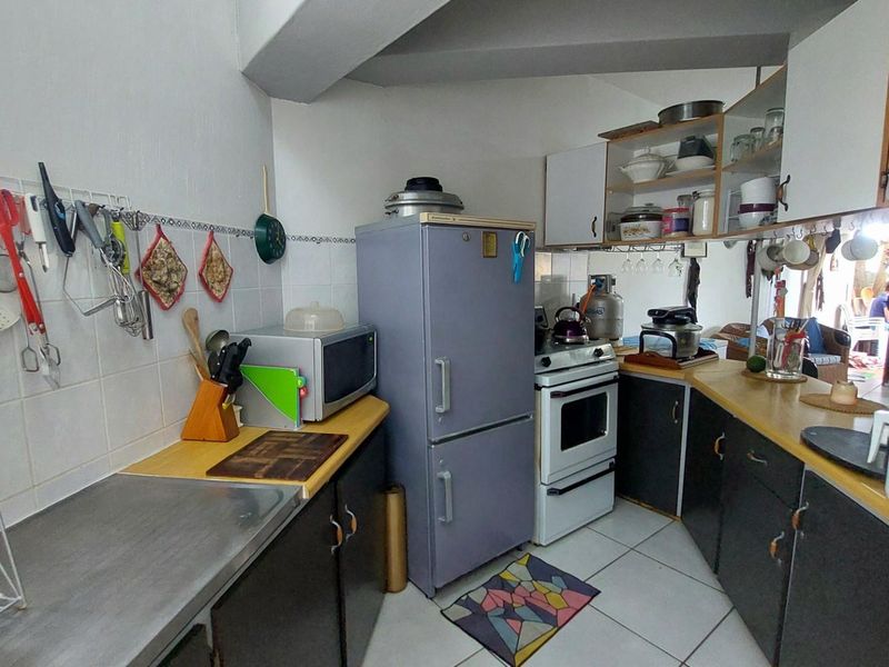 A compact, functional kitchen featuring dated cabinetry, tiled splashbacks, and a standard stove, offering potential for a modern renovation.