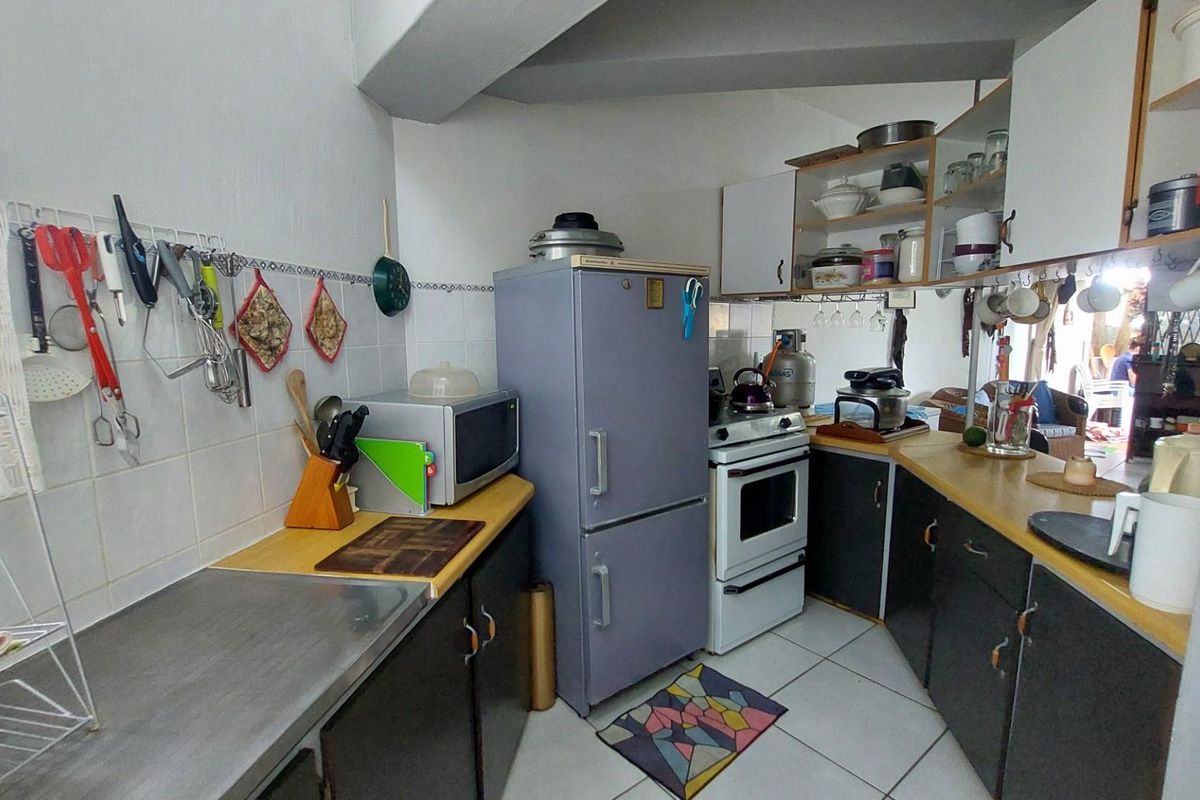 A compact, functional kitchen featuring dated cabinetry, tiled splashbacks, and a standard stove, offering potential for a modern renovation.