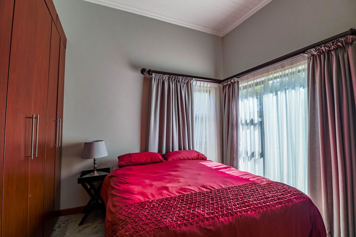 A well-maintained bedroom featuring built-in wardrobes, neutral wall tones, and direct access to the outdoors via sliding glass doors.