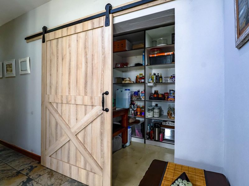A functional pantry or scullery area featuring a modern sliding barn door and extensive built-in shelving for organized storage.