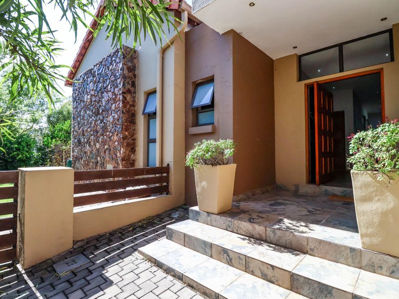 Front entrance featuring a stone-clad feature wall, tiled steps, and a timber panel door, leading into the main residence.