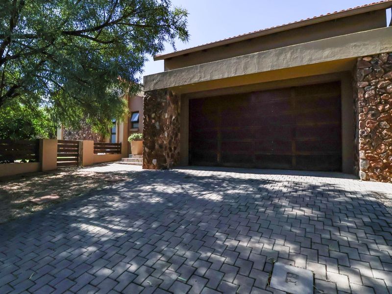 Front exterior view of the property featuring a paved driveway, stone-clad facade, and a secure garage entrance.
