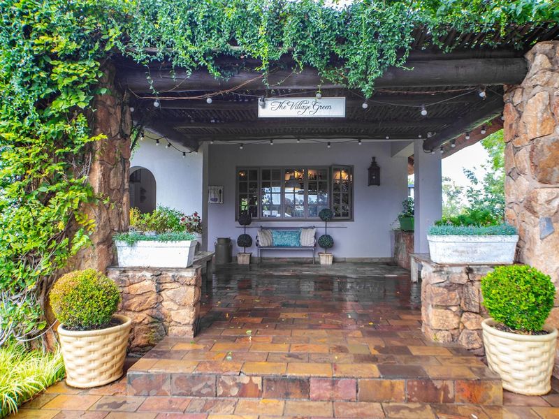 A charming covered patio area featuring rustic stone pillars, a timber pergola, and durable tiled flooring, creating an inviting outdoor entrance space.