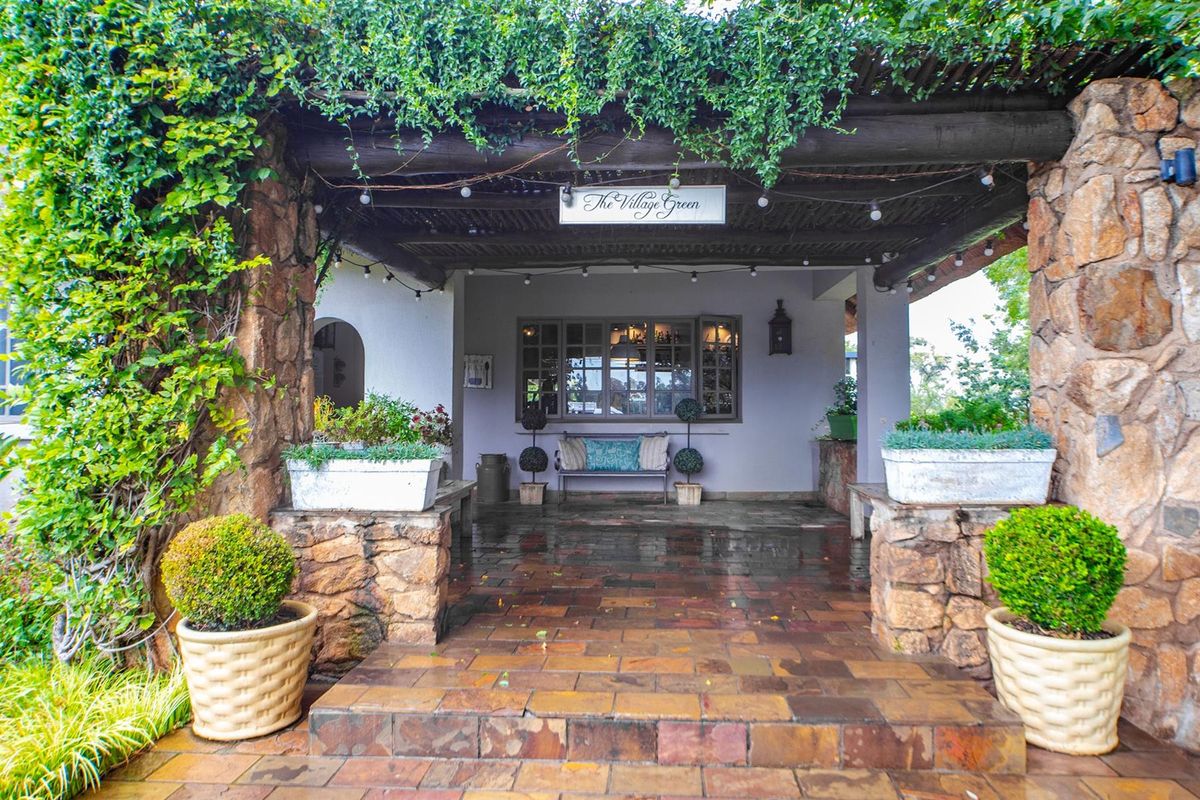 A charming covered patio area featuring rustic stone pillars, a timber pergola, and durable tiled flooring, creating an inviting outdoor entrance space.