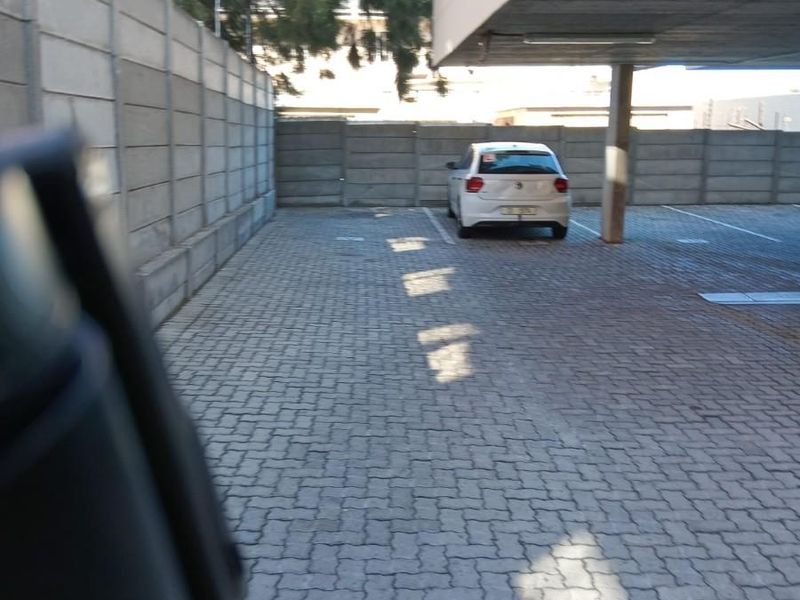 A covered parking area featuring paved ground, concrete support pillars, and secure precast concrete boundary walls.