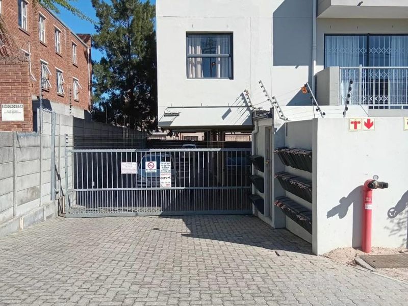 Front entrance of the apartment complex featuring a paved driveway, secure electric sliding gate, electric fencing, and wall-mounted mailboxes.