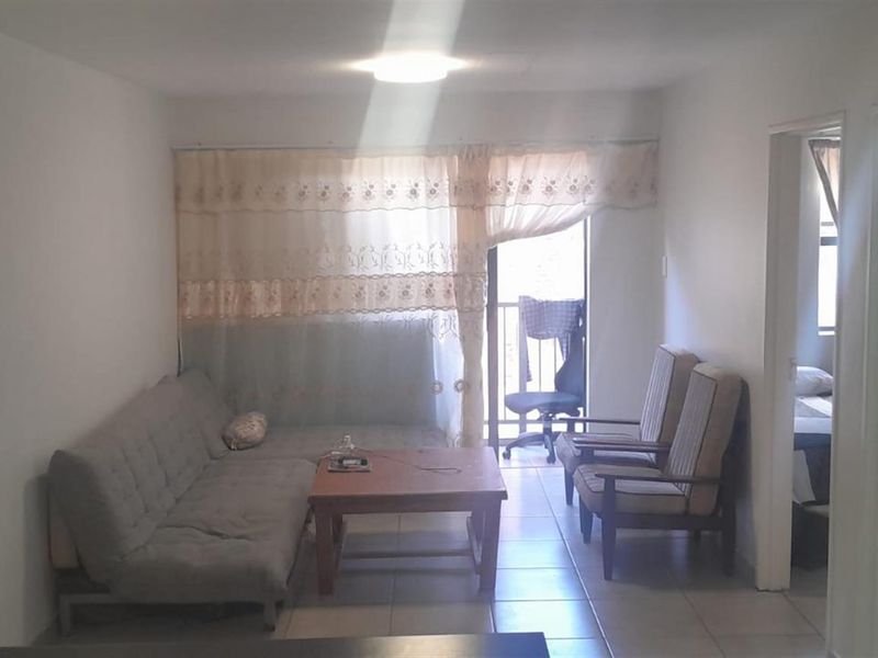 A functional living room area featuring tiled flooring and a sliding door providing access to an outdoor space.