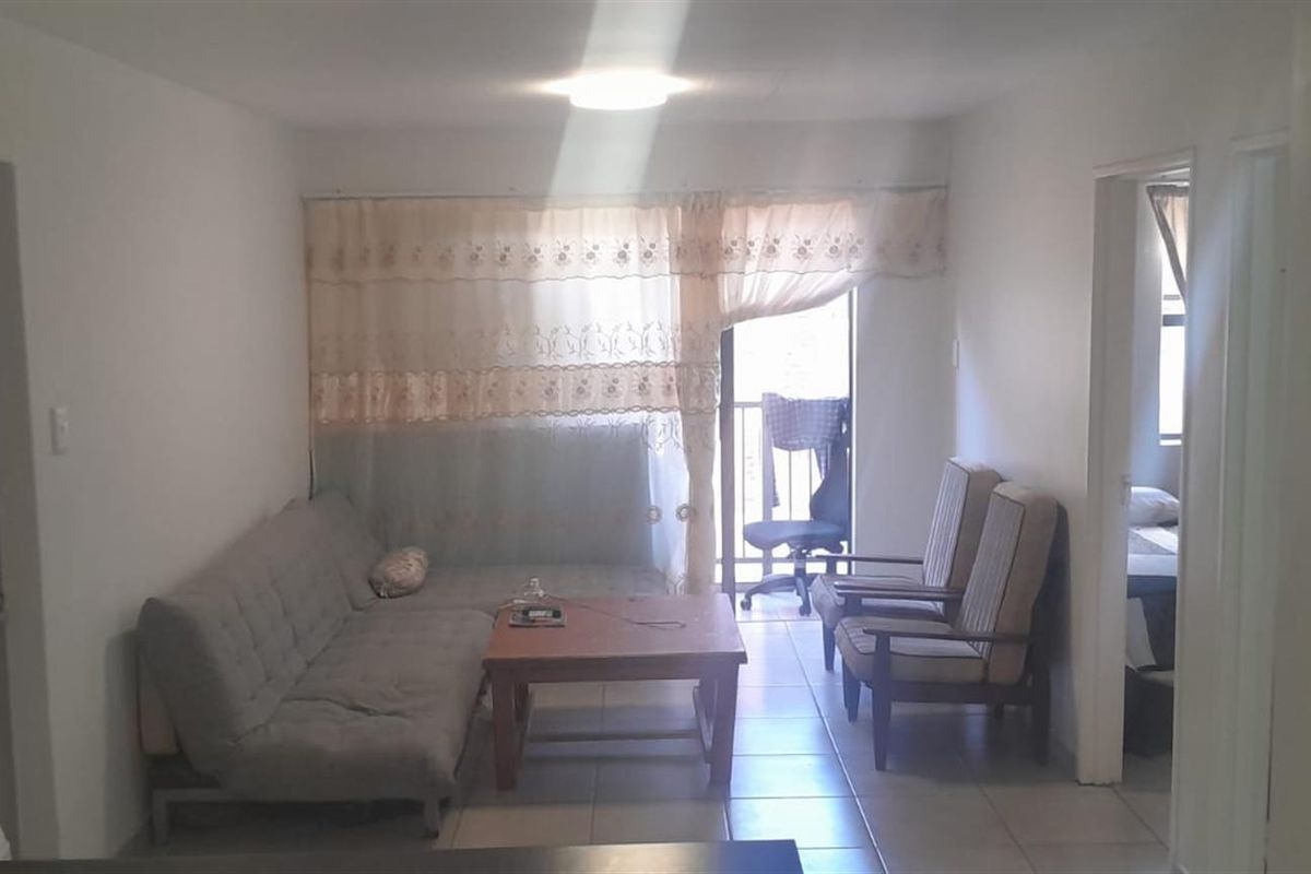 A functional living room area featuring tiled flooring and a sliding door providing access to an outdoor space.