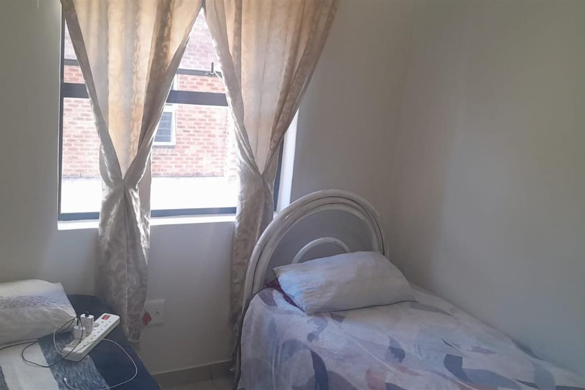 A simple bedroom featuring a window with natural light and standard electrical fixtures.