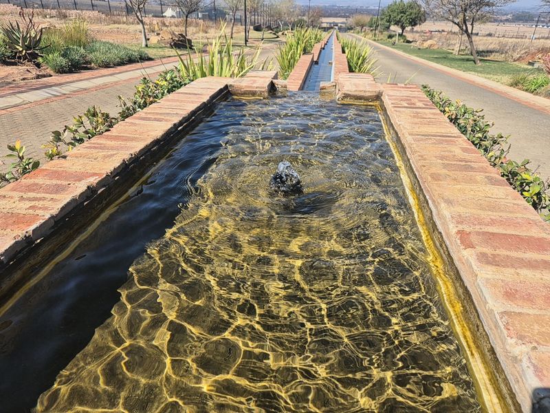 A well-maintained brick-lined water feature and fountain set within a landscaped garden area, providing an attractive aesthetic element to the property grounds.