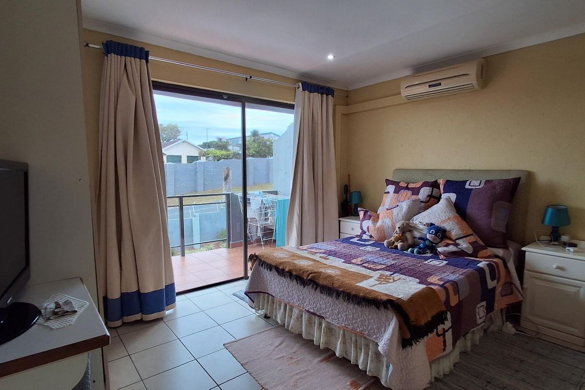 A bedroom featuring tiled flooring, a wall-mounted air conditioning unit, and sliding glass doors that open onto a private balcony.