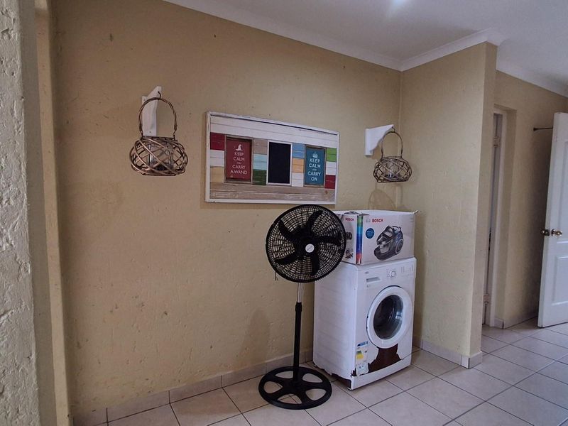 A functional laundry area featuring tiled flooring and a dedicated space for a washing machine.