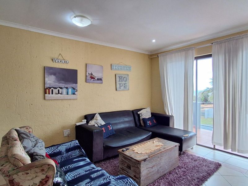 A living room featuring tiled flooring, textured walls, and large sliding glass doors providing access to an outdoor balcony area.