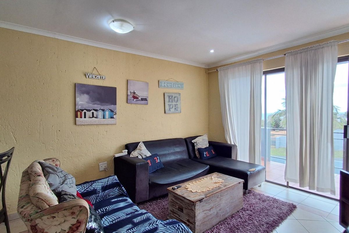 A living room featuring tiled flooring, textured walls, and large sliding glass doors providing access to an outdoor balcony area.