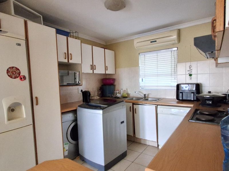 Functional kitchen featuring built-in cabinetry, tiled backsplash, integrated stove, and wall-mounted air conditioning unit.