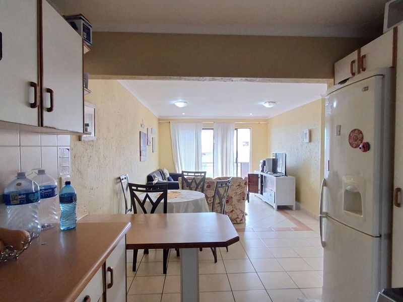 Open-plan kitchen and living area featuring tiled flooring, built-in cabinetry, and direct access to a balcony, creating a functional and connected living space.