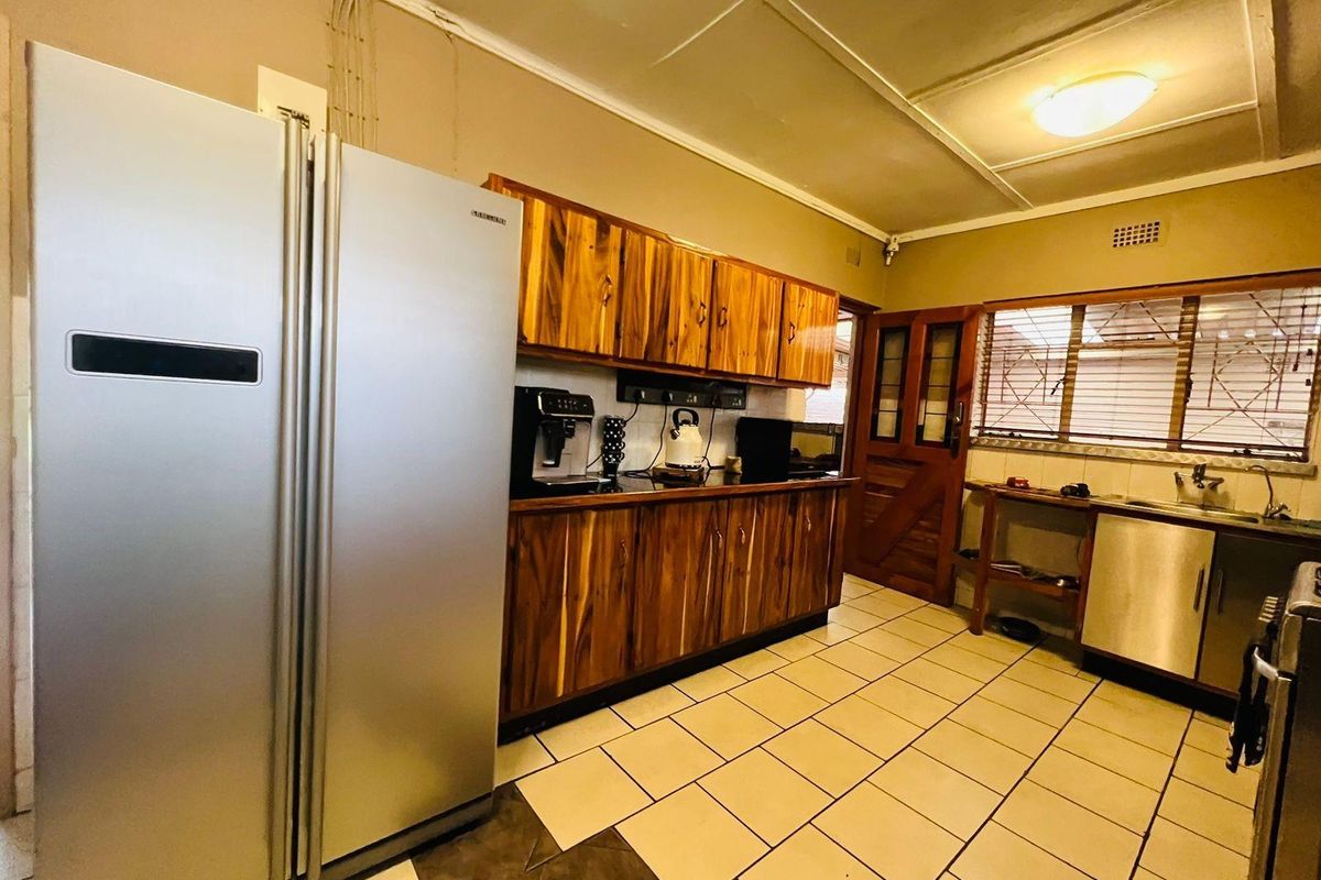 A functional kitchen featuring wooden cabinetry, tiled flooring, and a large double-door refrigerator, offering a practical layout for daily meal preparation.