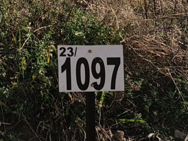 A close-up view of a property identification marker sign on a vacant residential plot.