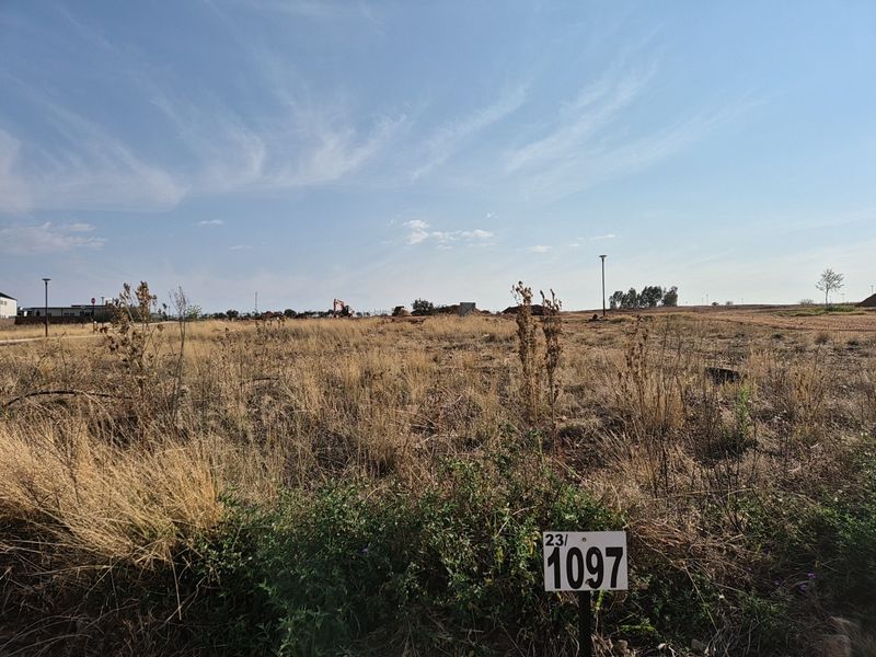A vacant residential plot of land featuring dry grass and a property marker, ready for development.