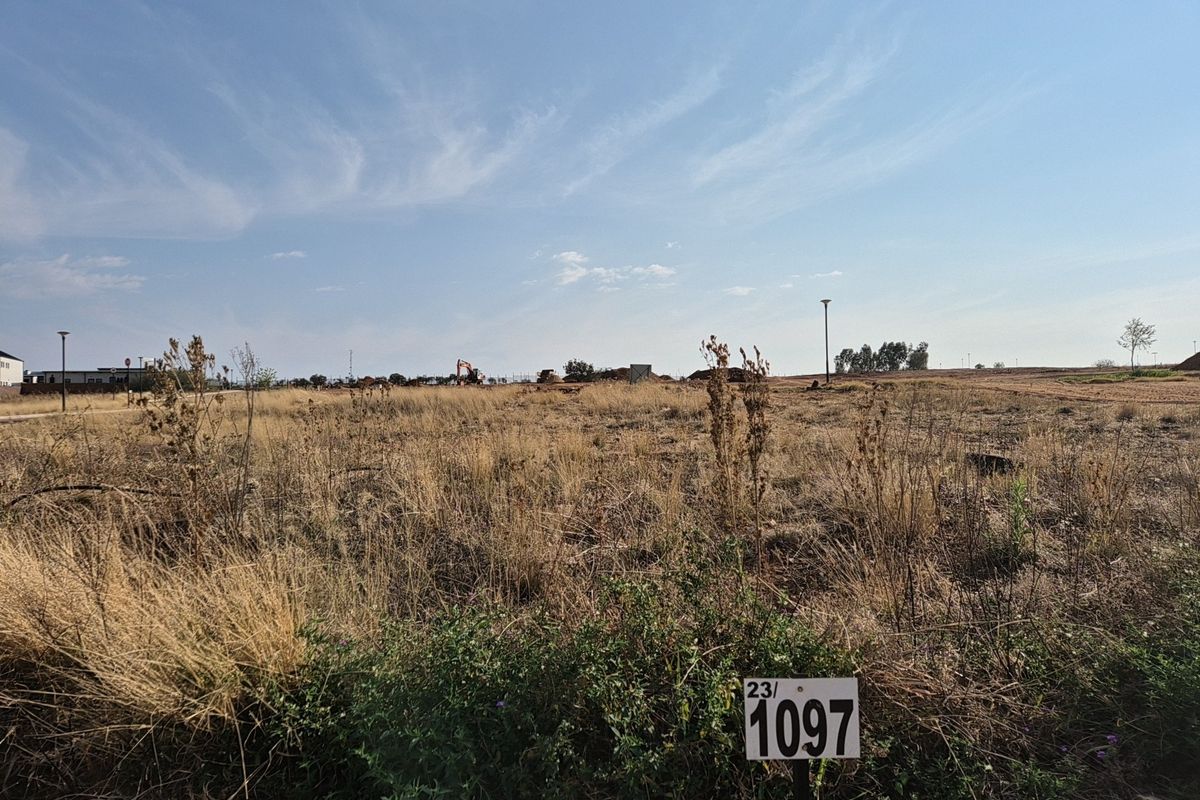 A vacant residential plot of land featuring dry grass and a property marker, ready for development.