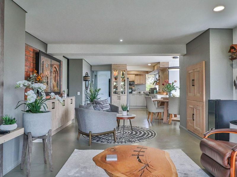 An open-plan living and dining area featuring polished concrete floors, exposed brick accents, and a modern kitchen with integrated cabinetry.