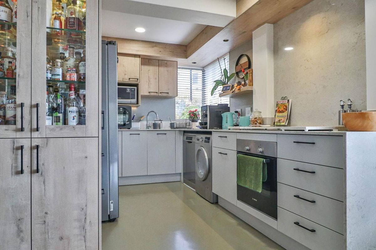 Modern kitchen featuring light-toned cabinetry, integrated oven, built-in microwave, and sleek stone-look splashback with recessed lighting.