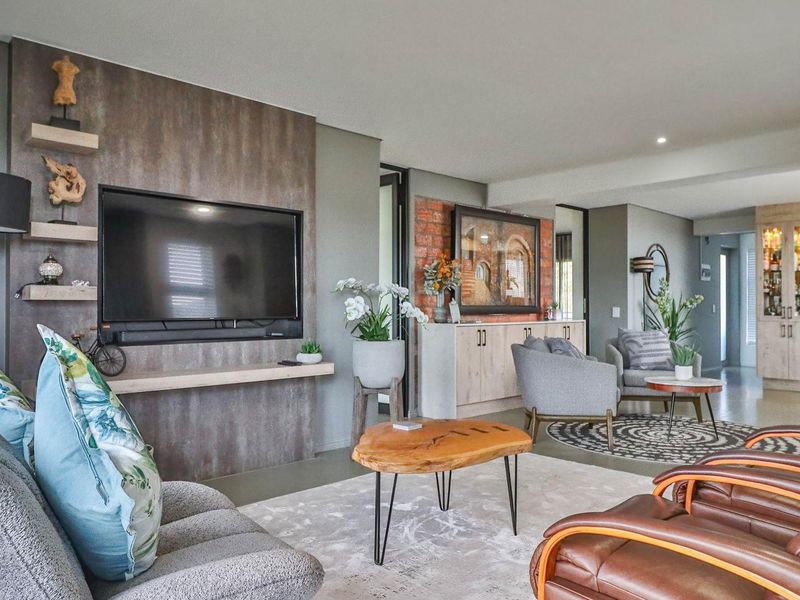 Spacious open-plan living area featuring a modern feature wall with integrated shelving, polished concrete flooring, and a seamless flow into the kitchen space.