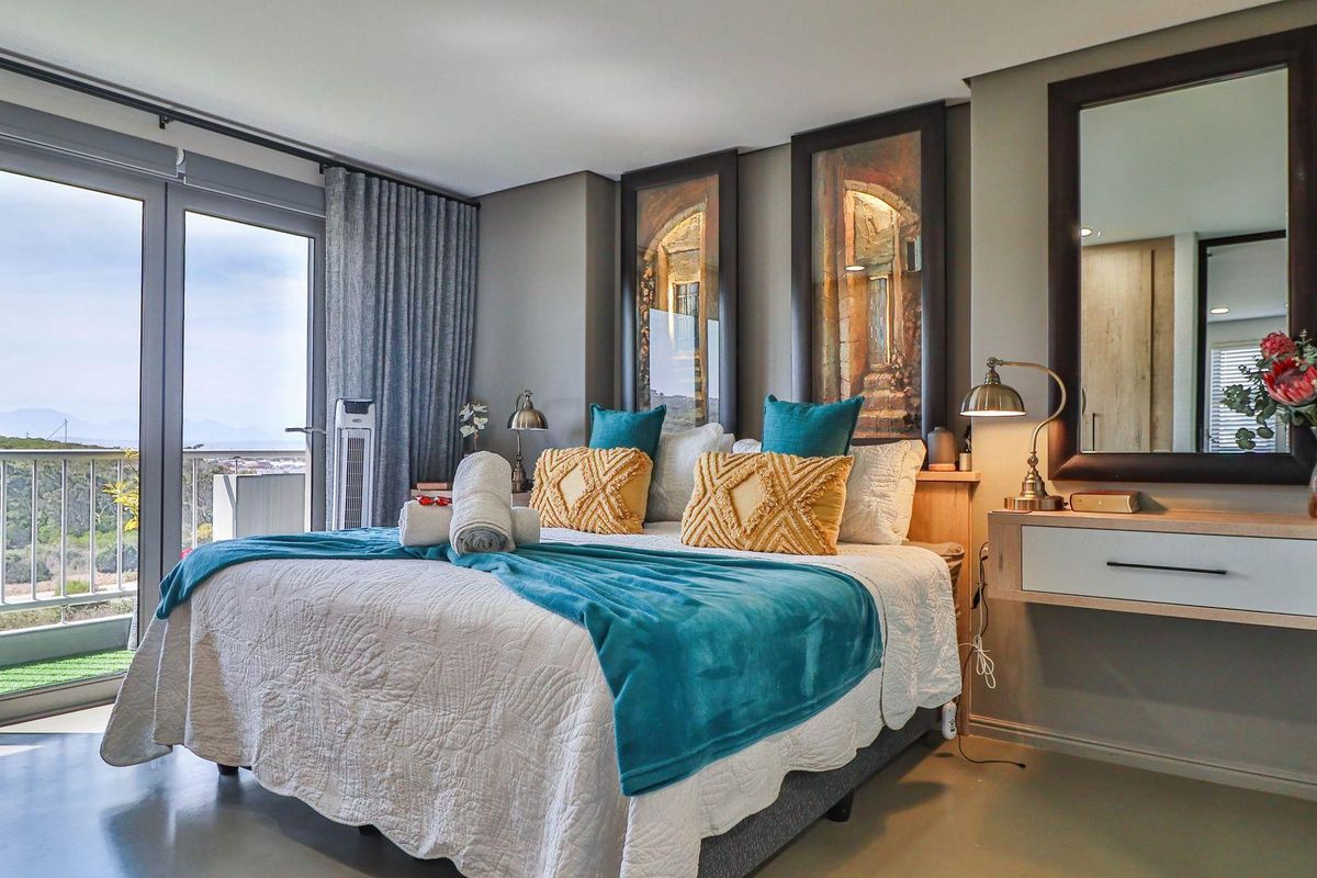 A well-maintained bedroom featuring a floating vanity, large glass sliding doors leading to a balcony, and neutral wall finishes.