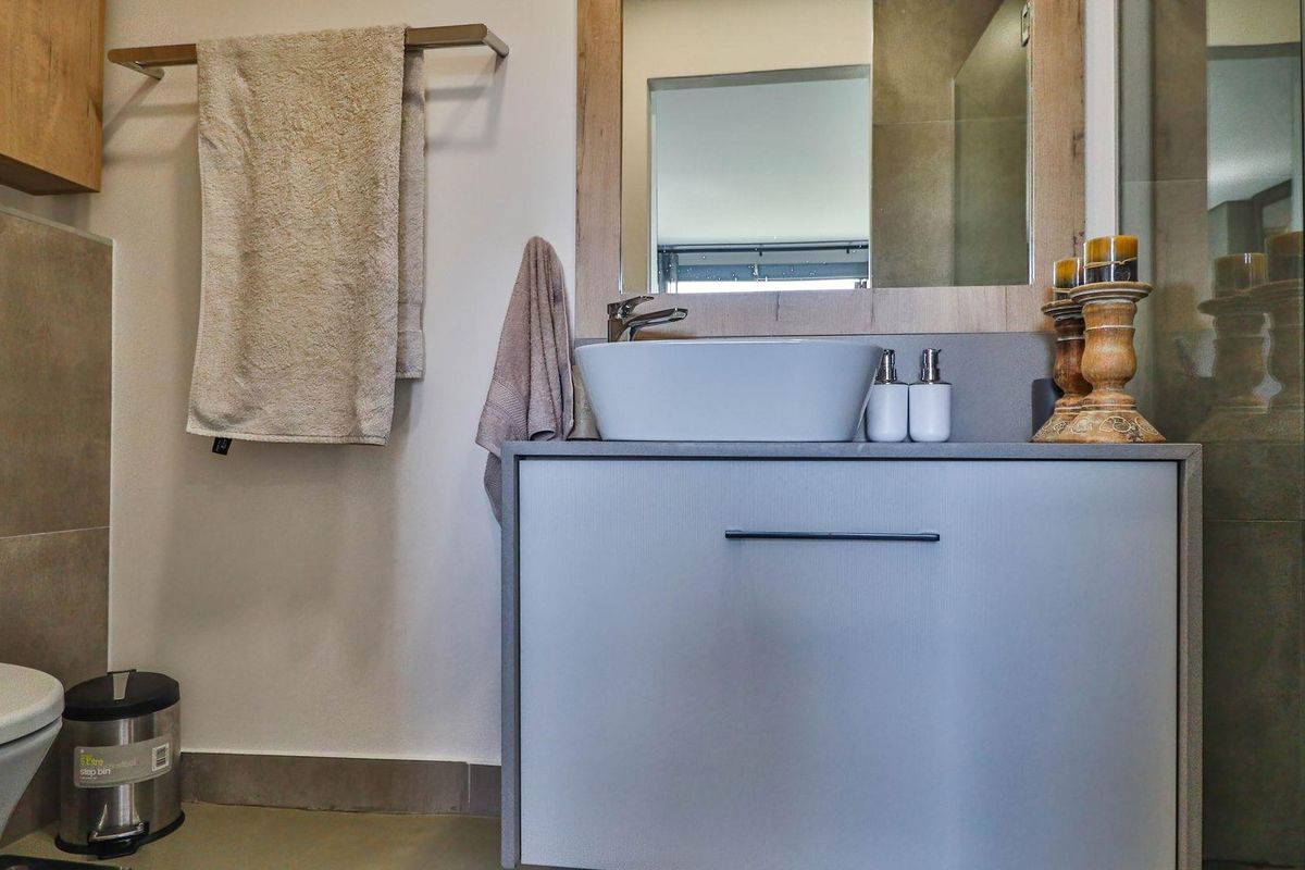 Modern bathroom featuring a sleek vanity with a vessel sink, wall-mounted mirror, and tiled shower enclosure.