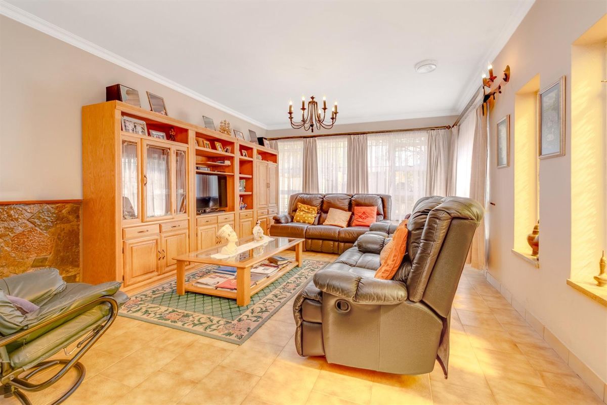 Spacious living room featuring tiled flooring, a stone-clad fireplace, and extensive built-in wooden cabinetry, offering a warm and functional family space.