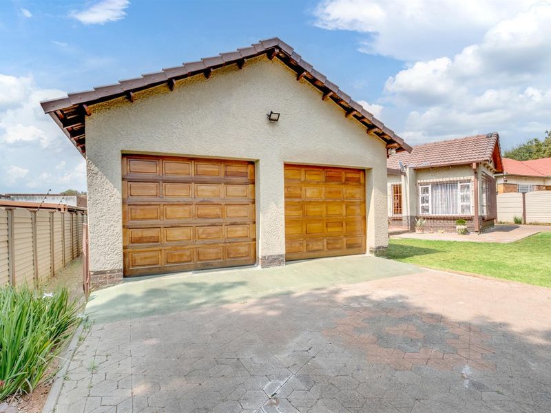A detached double garage with wooden doors, tiled roof, and paved driveway, situated on a residential property.
