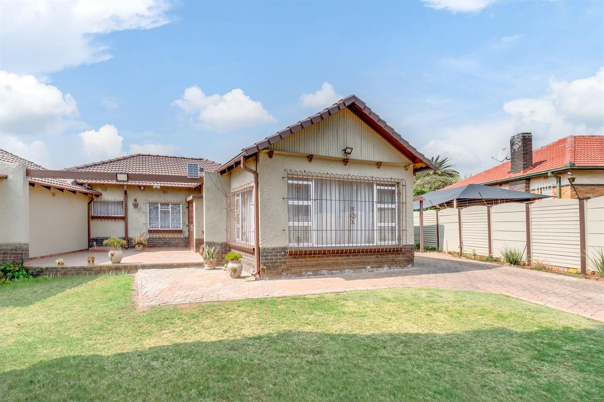 Rear view of the property featuring a paved patio area, lawn, and secure window treatments, showing a well-maintained exterior structure.